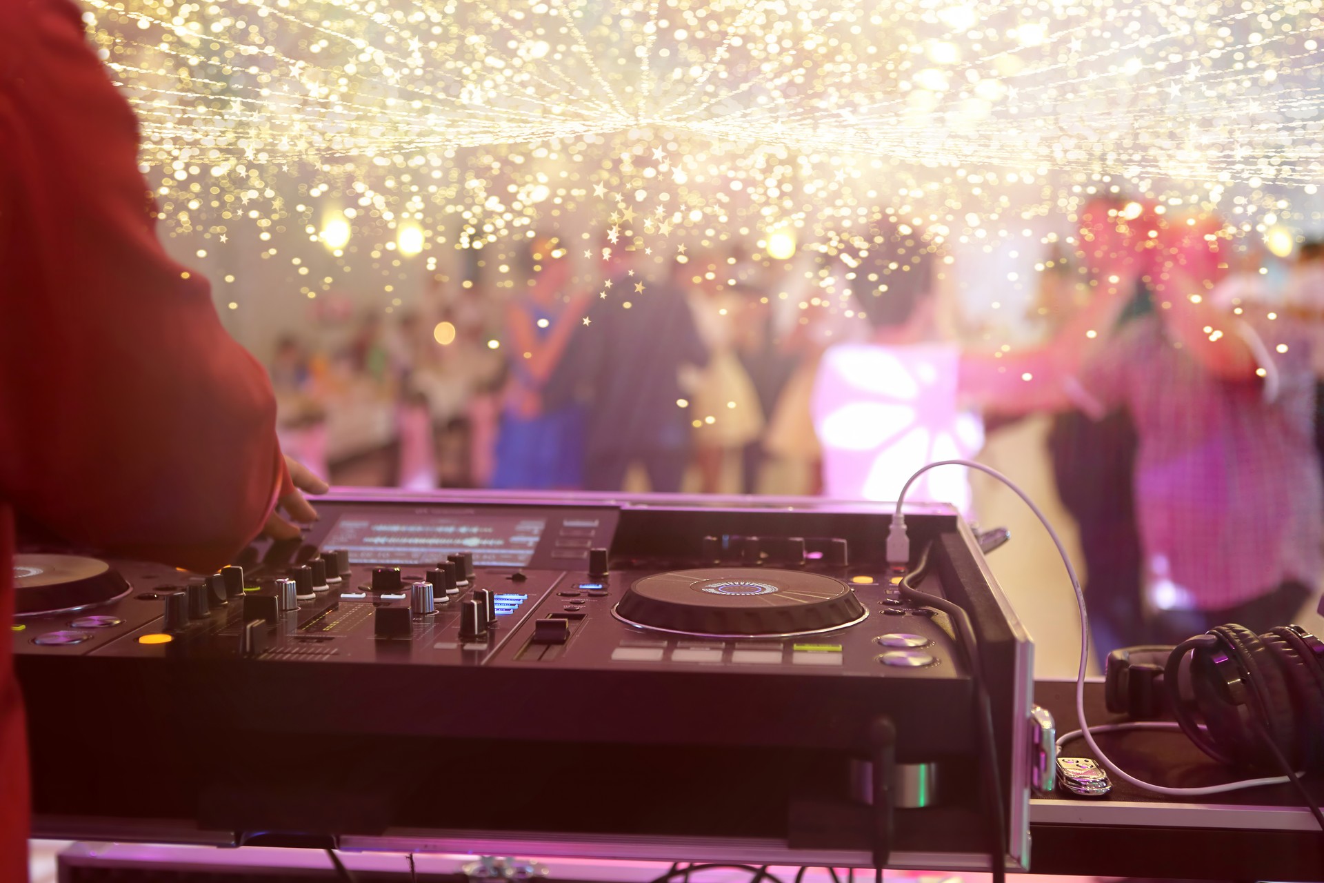 La console de mixage est jouée par le DJ et les couples qui dansent sur la piste de danse en arrière-plan